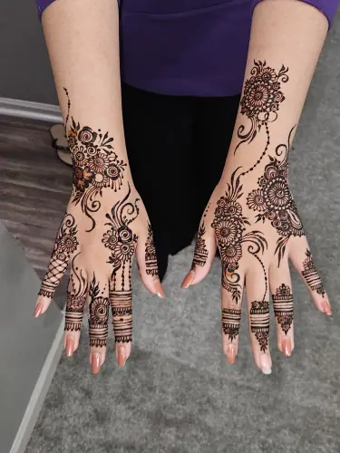 Two hands and forearms with long floral vines and detailed finger mehndi