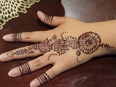 A floral henna medallion and a linked wrist cuff on the back of a hand