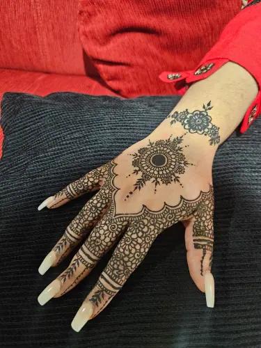 A circular floral henna medallion with finely patterned fingers