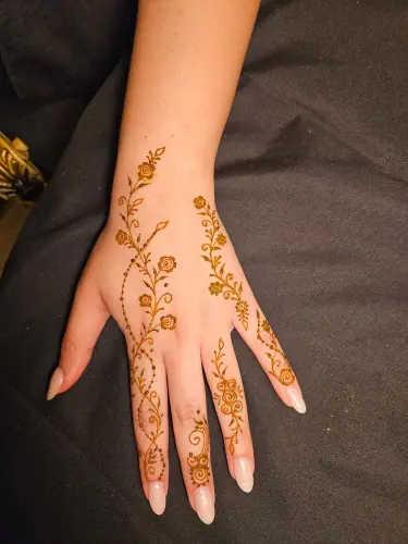 Minimal orange-brown henna flowers and a leafy vine across a hand