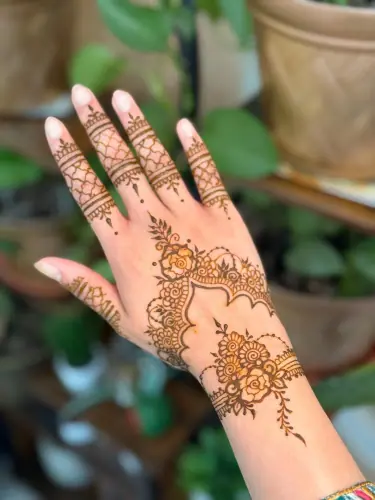 A fine lattice henna pattern linking flowers along a hand and wrist