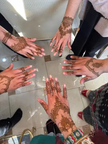 Several henna-decorated hands arranged in a circle around a reflective surface
