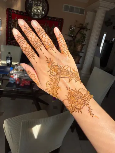Floral henna and fine finger lattice on a hand in sunlight