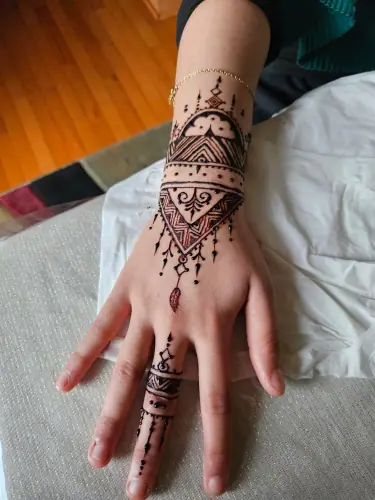 A geometric henna design with crescent details and fine finger chains