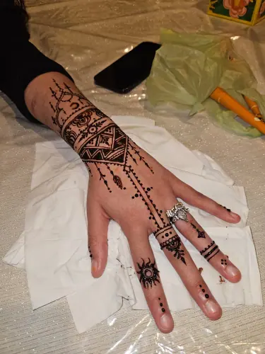 A henna wrist cuff with triangular borders and delicate hanging motifs