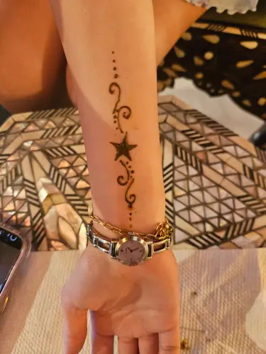 A crescent moon, stars and a fine henna swirl on the inner forearm