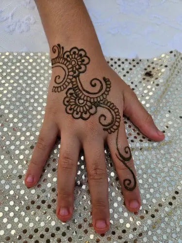 A bold curving floral henna motif across the back of a hand