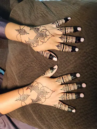 Two hands with asymmetric flowering henna vines and dark striped fingertips