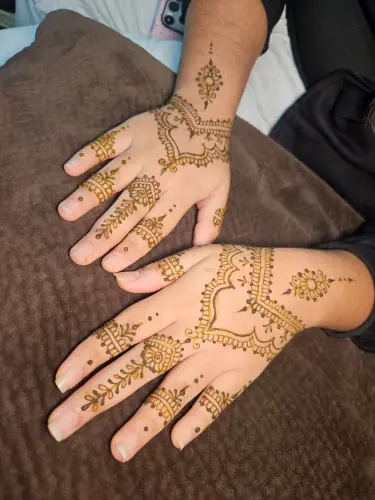 Two palms with fine floral henna chains, small medallions and patterned fingers