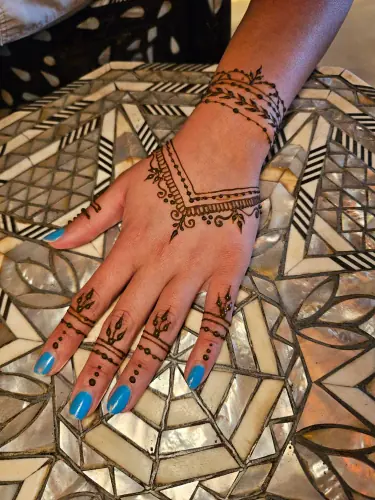 A geometric henna wrist cuff with a central flower and pointed borders
