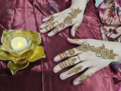 Two hands with contrasting floral henna compositions on burgundy fabric