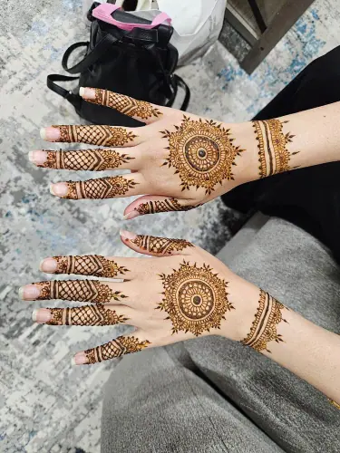 Two hands with circular henna medallions, detailed fingers and wrist bands