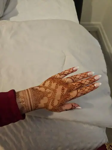 A hand with an ornate floral henna cuff resting on pale fabric