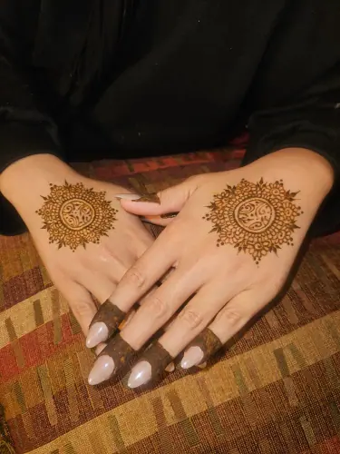 Two hands with matching round floral henna medallions and fine finger details