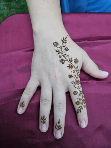 A minimal leafy henna vine flowing across a hand on pink fabric