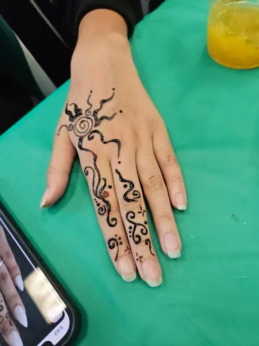 A bold scrolling henna design with curls and a flower on green fabric